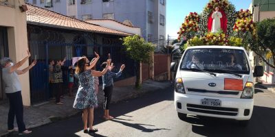 Devotos do beato Padre Eustáquio levantando as mãos e aplaudindo a passagem do carro-andor com a imagem do bem-aventurado.