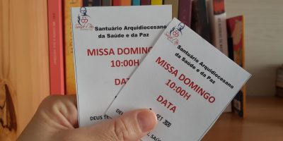 Uma mão segura duas senhas para participação das missas presenciais do Santuário