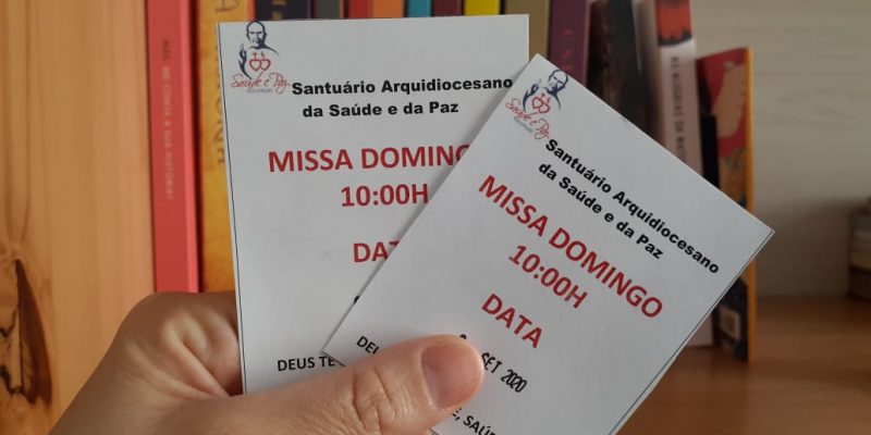 Uma mão segura duas senhas para participação das missas presenciais do Santuário